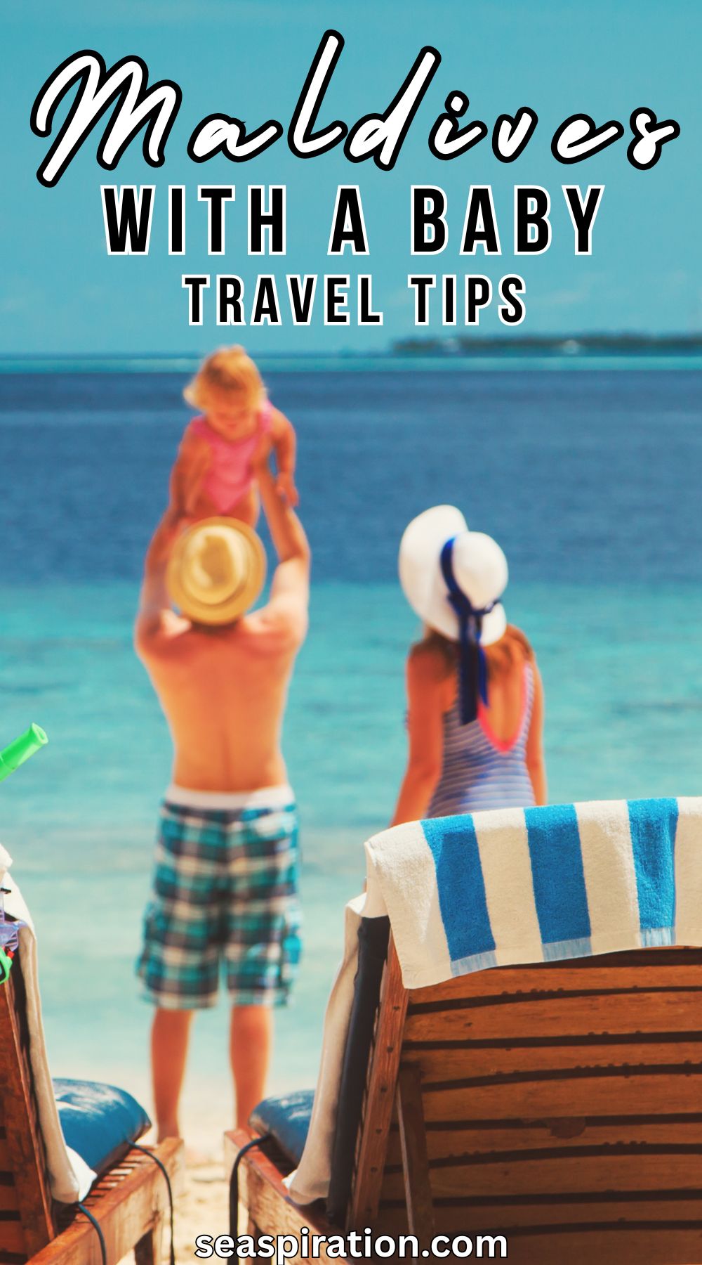 happy family with a small kid standing on a tropical beach near the water, behind sunbeds