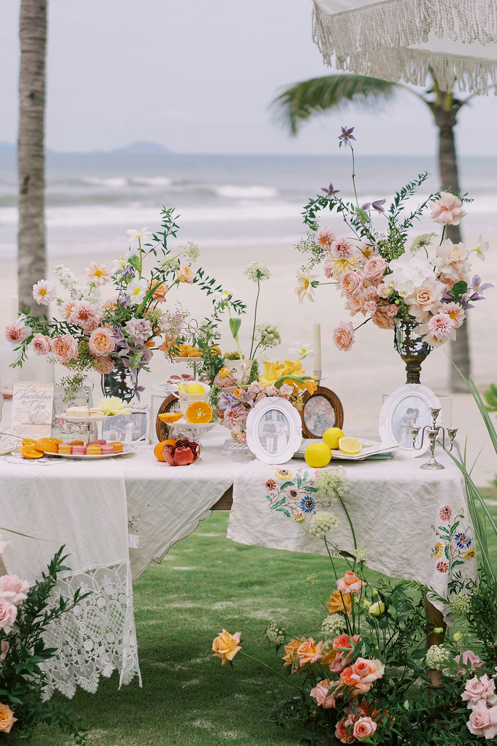 beach wedding setup with floral arrangements in shades of pink, orange, and white