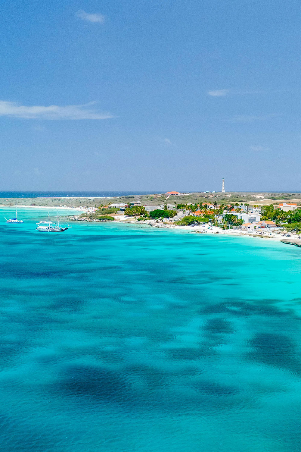 Aruba's rugged shoreline with turquoise water, with the California Lighthouse in the background