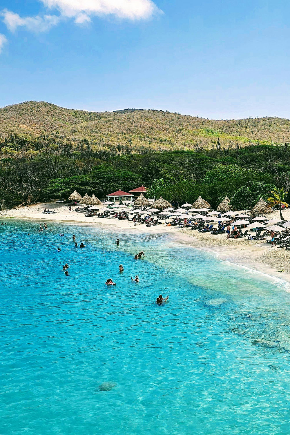 the famous Grote Knip beach in Curacao with turquoise waters and white sandy shore, surrounded by cliffs and hills