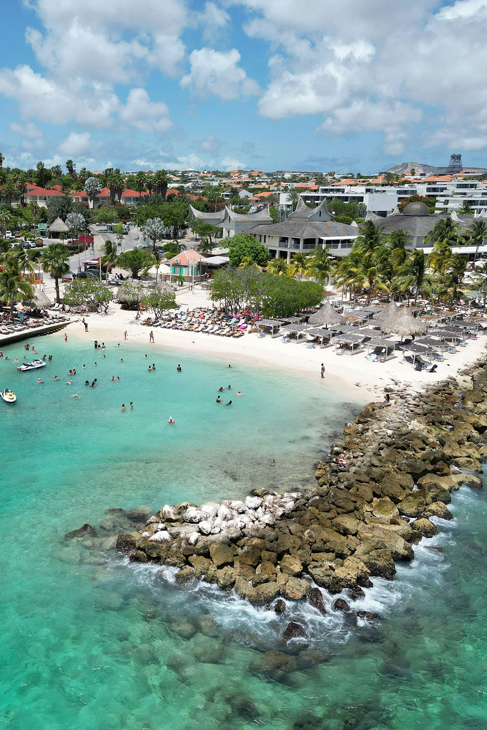 popular tourist beach of Jan Thiel known for its white sand, turquoise waters, and vibrant atmosphere with people enjoying the sea and sunbathing on the shore