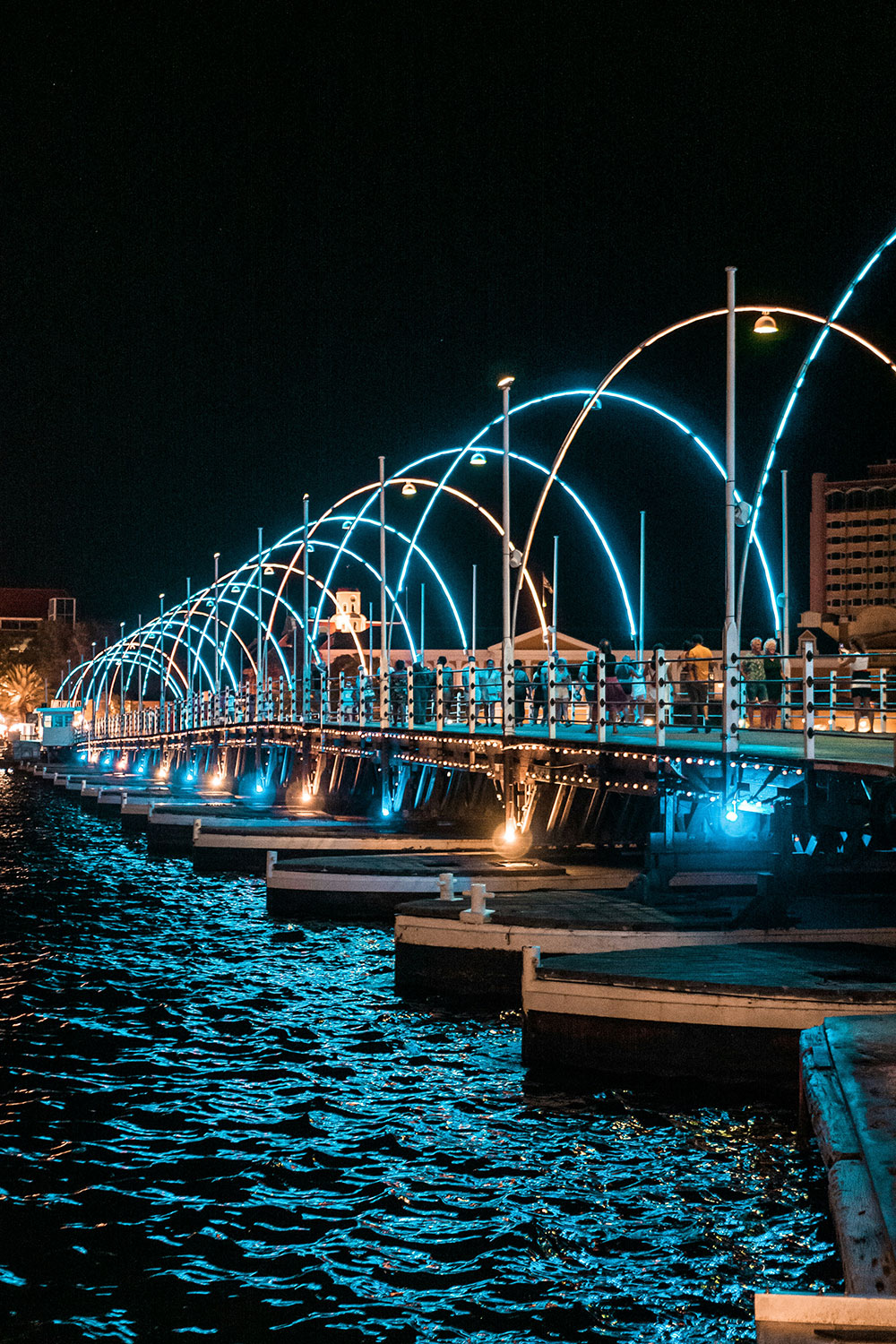 night view of the Queen Emma Bridge in Curacao with people walking on it