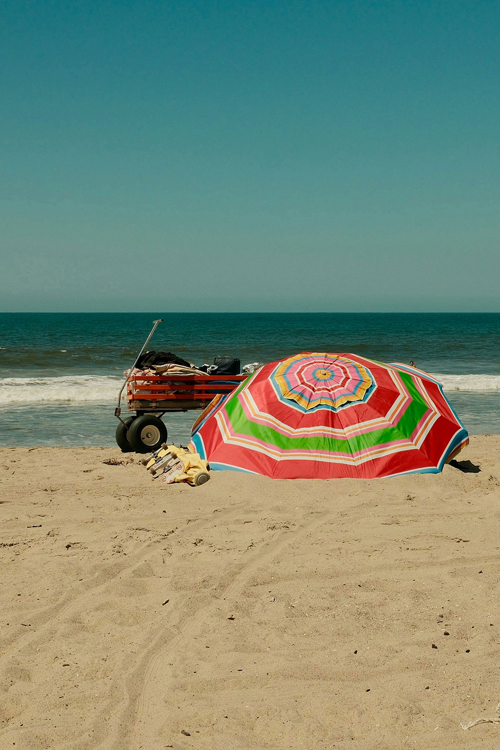 beach wagon and sun umbrella on the sand near the water
